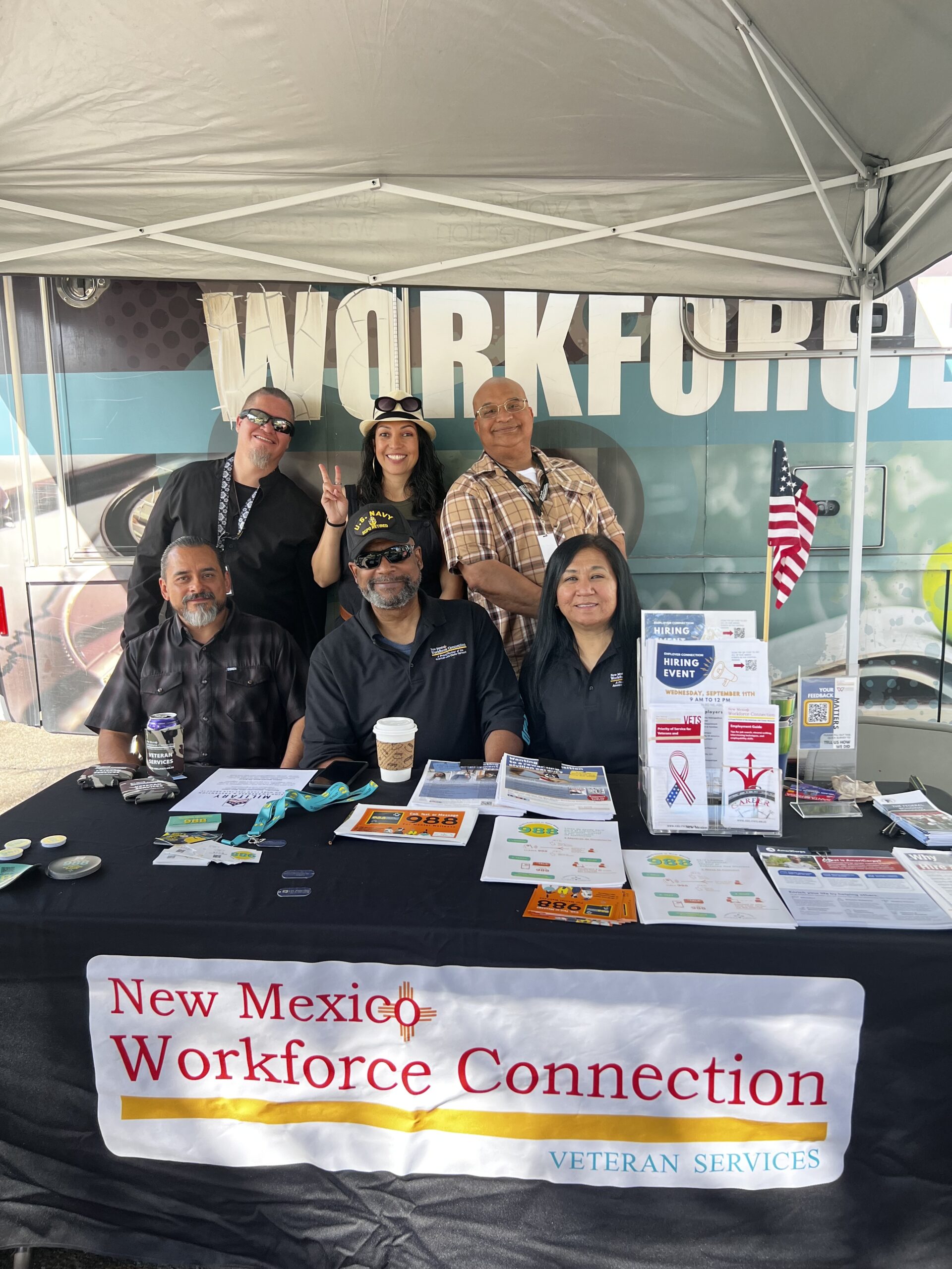 A group of men and women veterans seated at the New Mexico State Fair at the Veterans table, smiling